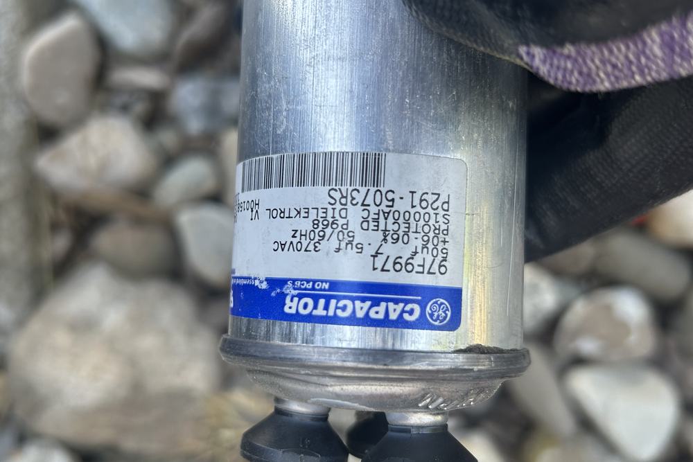 GE run capacitor held in a gloved hand