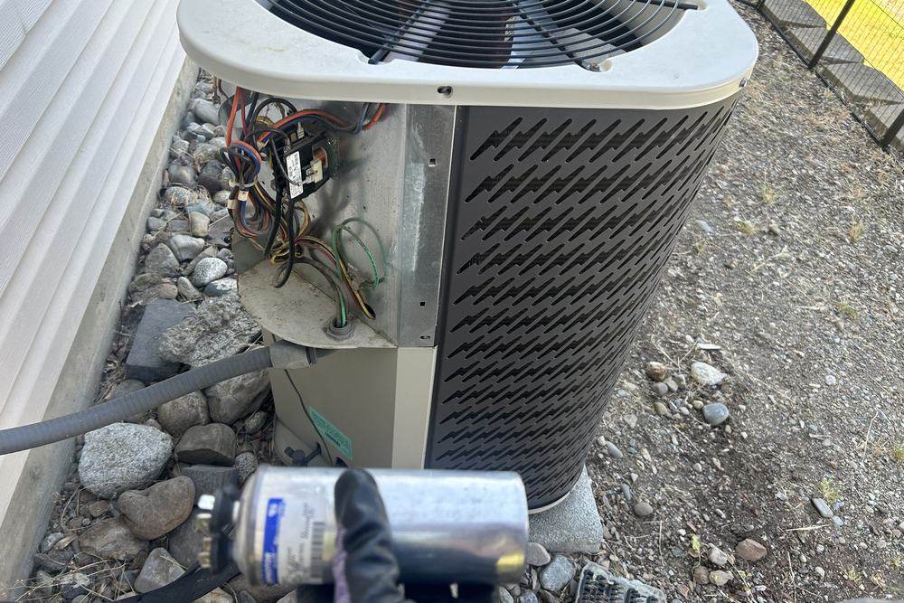 Outdoor unit with panel open and a capacitor in the foreground