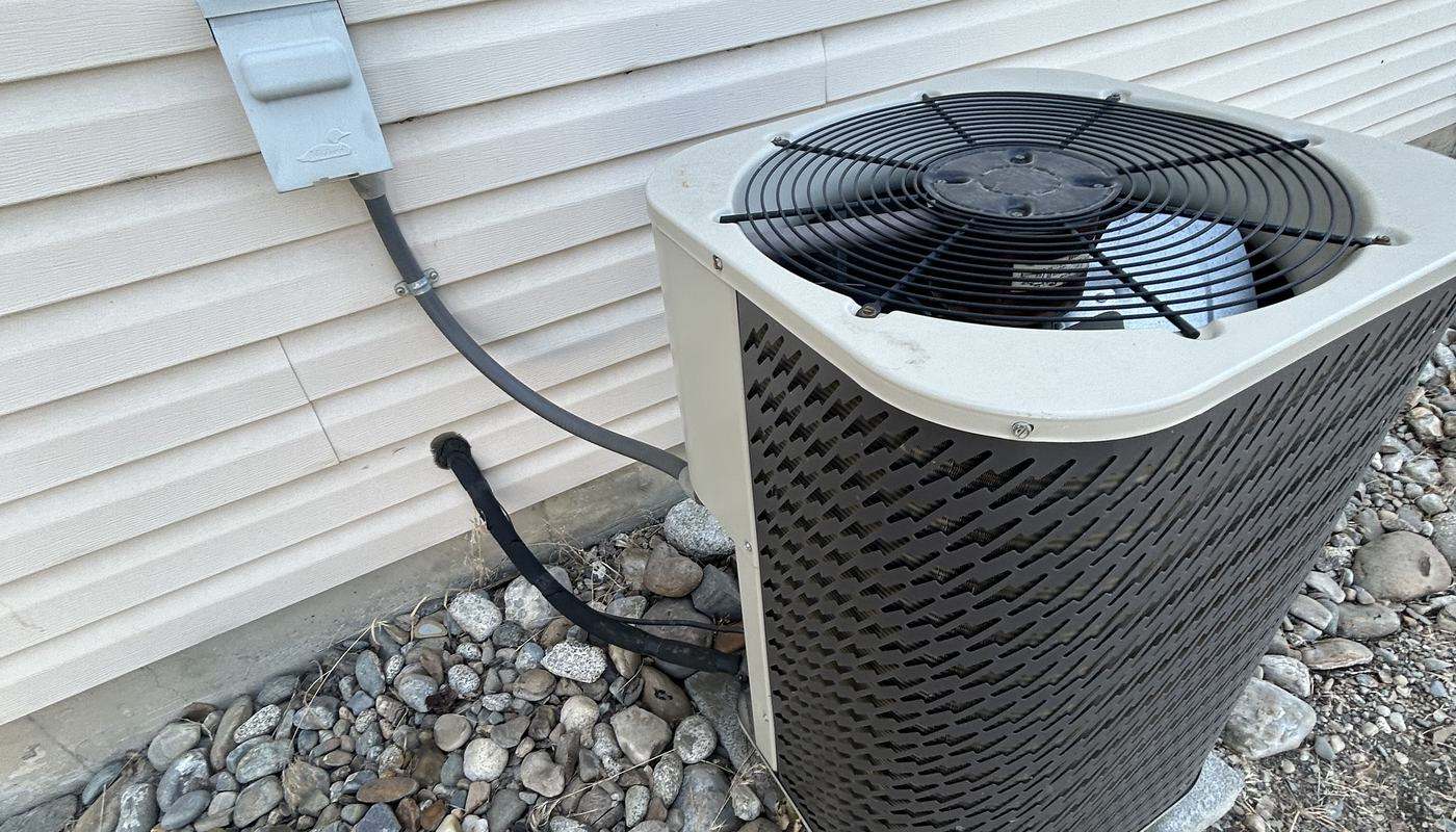 Outdoor heat pump beside a house on a gravel bed