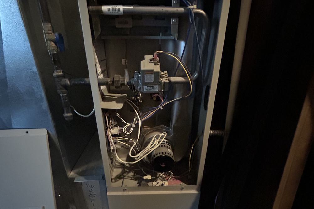 Furnace cabinet open beside an air handler in a basement