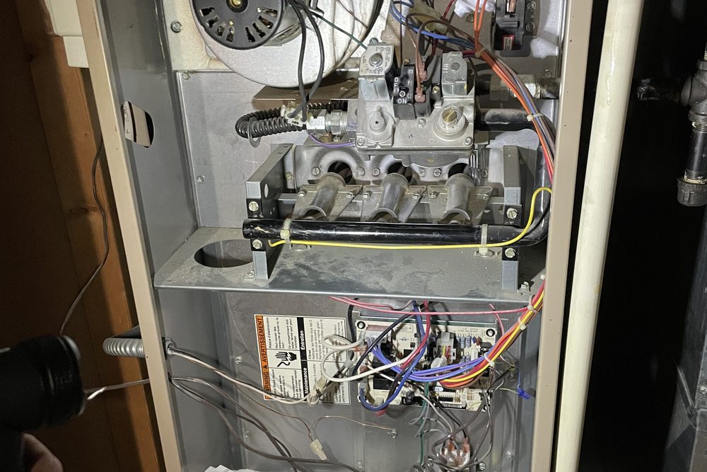 Older furnace with the cabinet open showing gas valve and control board