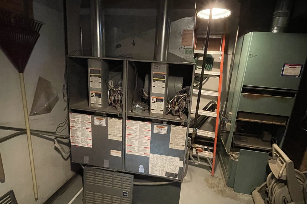 Two furnaces side by side in a basement mechanical room
