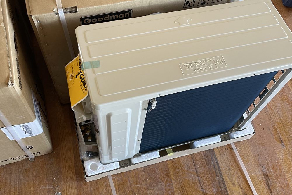 New ductless outdoor unit unboxed on a wood floor