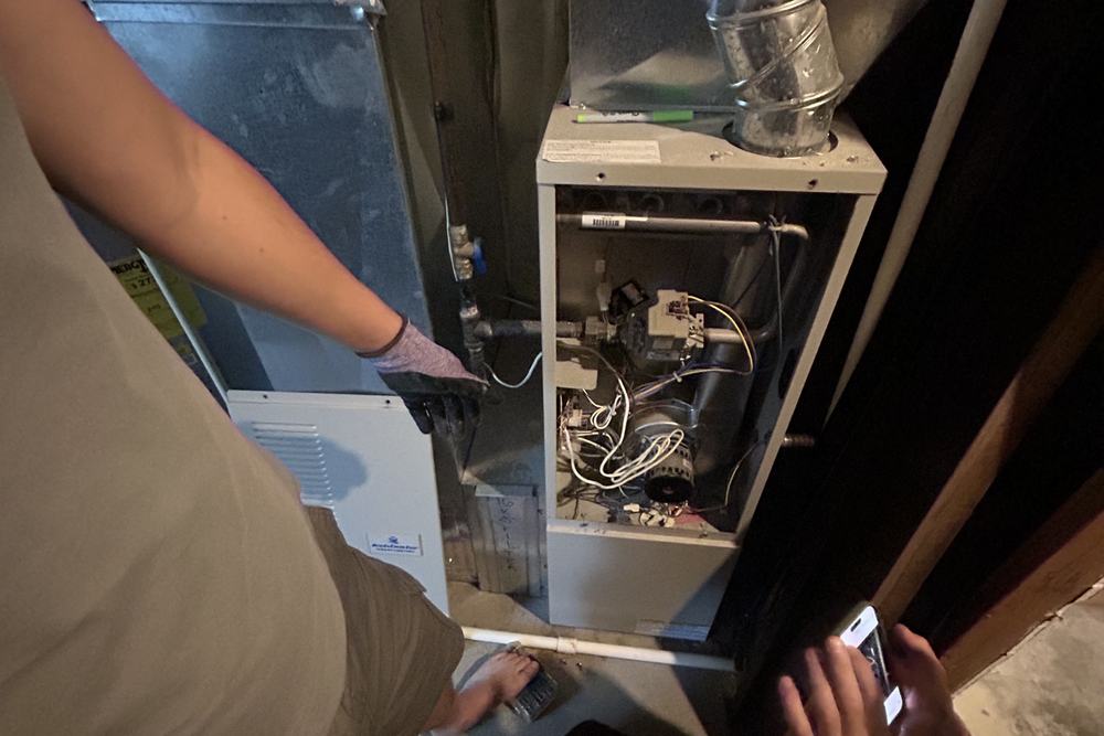 Two people looking into an open furnace cabinet